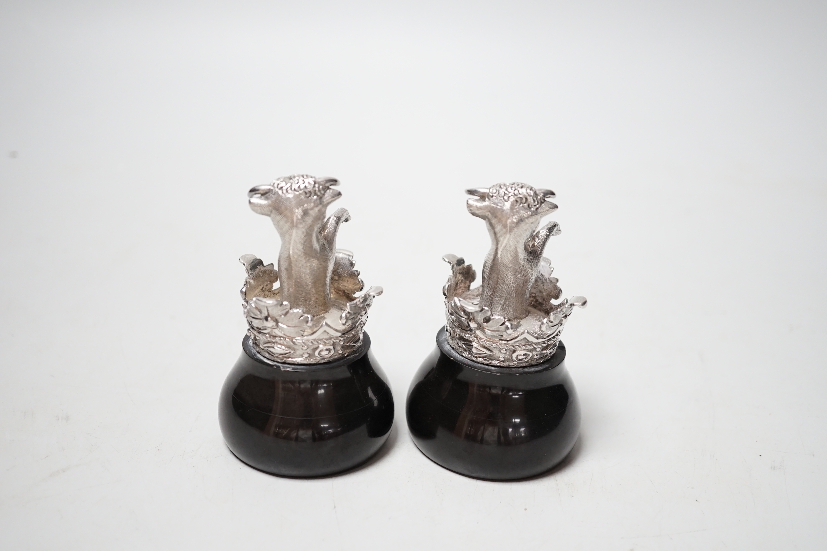 A pair of silver heraldic crests, modelled as rearing bull's within a coronet, on ebonised bases, probably copies of the pediments at Eridge Park, Kent, Mitchell Bosley & Co?, Birmingham, 1899, height 95mm.